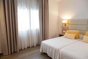 波蒂纳茨拉斯归纳旅馆的一间卧室配有一张带黄色枕头的床和一扇窗户