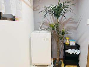 大阪Namba Shinsaibashi 10 mins Reiko guest house的一间设有冰箱和两株盆栽植物的房间