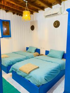 达哈布Blue House in Lighthouse的配有2张床的蓝色和白色墙壁客房