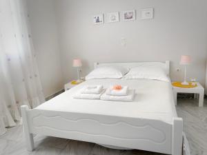 波多河丽Fairy home Porto Heli的一张带2条毛巾和2张桌子的白色床