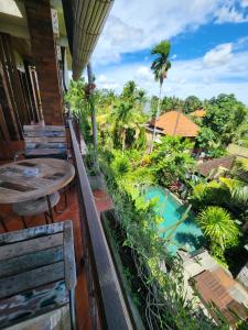 乌布BUDA AMITABA的享有游泳池和棕榈树景致的阳台