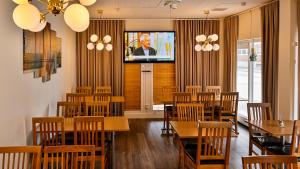 哈尔姆斯塔德阿玛德斯酒店的餐厅设有木桌、椅子和电视。