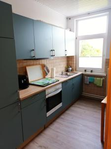 费马恩Ferienwohnung am Dorfteich的厨房配有蓝色橱柜、水槽和窗户。