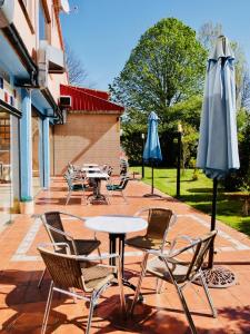 蓬特德乌梅Hotel Eumesa的一个带桌椅和遮阳伞的庭院。