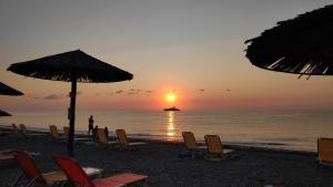 普拉卡利特索罗Camping Mitikas and Bungalows的海滩上的一组椅子和遮阳伞,伴随着日落