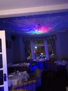 布莱克浦The Glenroy Guest House的一间拥有紫色和绿灯的天花板用餐室