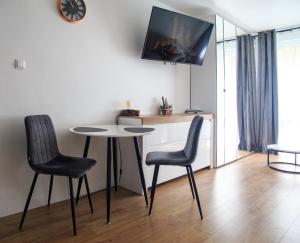 萨诺克Studio dla Dwojga的一间设有桌子、两把椅子和时钟的房间