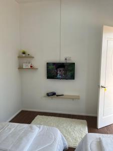 瓜拉丁加奴A’Casa Cottage的一间白色墙壁上配有电视的卧室
