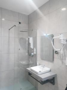米兰中央车站酒店的白色的浴室设有水槽和淋浴。