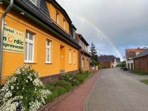 吕本瑙斯普利森林北欧酒店的黄色房子后面的天空中的一个彩虹