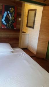 安东尼奥港Villa Rasta - Ocean View Bungalows的卧室配有白色的床和墙上的绘画作品
