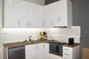 卡拉马塔KAPA Central Apartment的厨房配有白色橱柜、水槽和微波炉