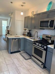 费城2bd Spacious S. Philly Row-House, Wi-Fi & 1.5 bath的厨房配有灰色橱柜、炉灶和水槽。