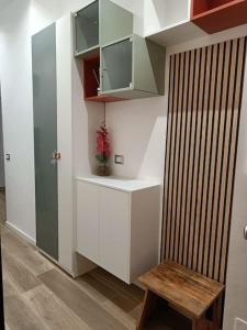 米兰Lucania25的小厨房配有白色橱柜和木凳
