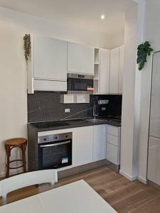 米兰Lucania25的厨房配有白色橱柜和炉灶烤箱。
