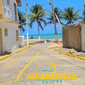雅帕拉廷加Japaratinga Suites的棕榈树海滩前的街道