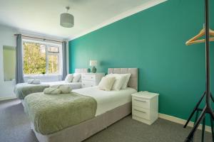 彼得伯勒Raymond James Accommodation, sleeps up to 7, free parking, full amenities and garden的一间卧室设有两张床和蓝色的墙壁