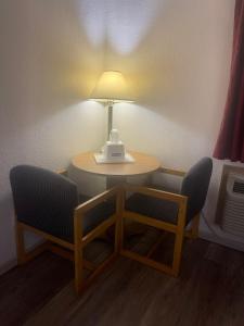 章克申城Travelodge by Wyndham Junction City的一张桌子,上面有两把椅子和一盏灯