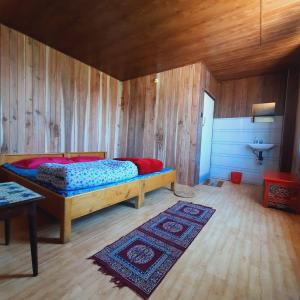 SombāriLali Gurash Homestay - Okhrey的卧室配有一张床铺,位于带木墙的房间内