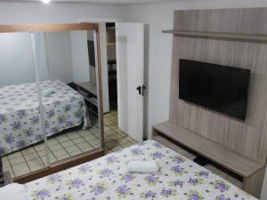 圣路易斯Flat Number One - Ponta D'areia - Ferreira Hospedagens的一间卧室配有一张床、一台电视和一面镜子