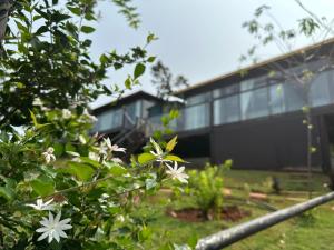 Gia NghĩaPhuong Nam Gia Trang Farmstay的前面有白色花的黑色建筑