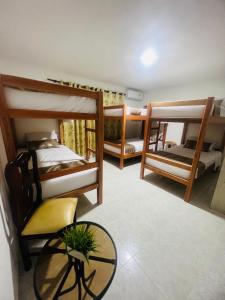 圣玛尔塔Hostal Casa San Pedro的客房设有三张双层床和一张桌子。