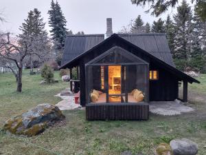 PuisePuise saunahouse and outdoor kitchen at Matsalu Nature Park的一座黑色的小房子,在田野上设有窗户