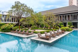 曼谷Villa Deva Resort & Hotel Bangkok的一座带躺椅的游泳池和一座建筑