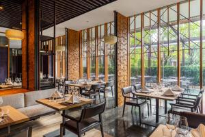 曼谷Villa Deva Resort & Hotel Bangkok的餐厅设有桌椅和大窗户。