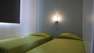 卢米奥CAMPING MONTE ORTU的墙上有灯的房间里设有两张床