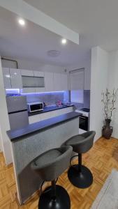 萨拉热窝Aya apartment Sarajevo的厨房在柜台前设有两个吧台凳