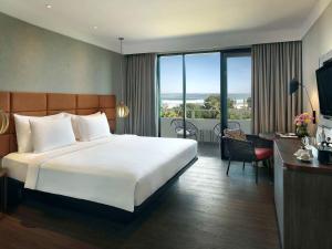 勒吉安巴厘岛勒吉安海滩铂尔曼酒店的酒店客房设有一张大床和一个阳台。