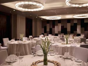 勒吉安巴厘岛勒吉安海滩铂尔曼酒店的宴会厅配有白色的桌子和白色的椅子