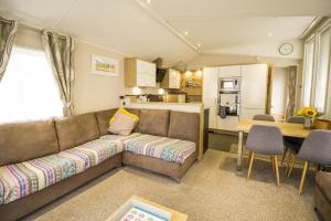 大雅茅斯Luxury Caravan With Decking Nearby Scratby Beach In Norfolk Ref 50001bm的带沙发和桌子的客厅以及厨房。