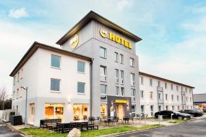 卡塞尔B&B Hotel Kassel-Süd的白色的建筑,上面有金色的标志