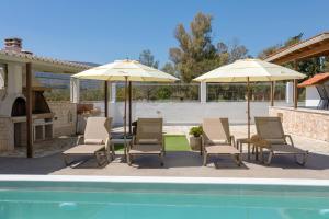 拉加纳斯Ilenia's 3 Bedroom House With Private Pool的一组椅子和遮阳伞,位于游泳池旁