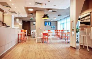 卡托维兹B&B Hotel Katowice Centrum的一间带橙色椅子的餐厅以及一间带柜台的酒吧