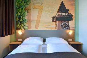 格拉茨B&B Hotel Graz City-Süd的一间卧室设有两张床,墙上挂着一个时钟。