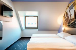 基尔B&B Hotel Kiel-Holstenbrücke的酒店客房设有两张床和窗户。