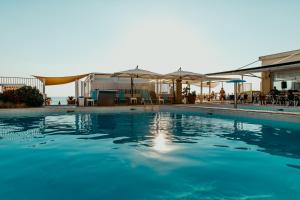 帕利努罗萨林恩酒店的一个带蓝色水、桌子和遮阳伞的游泳池
