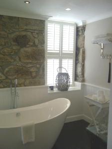 圣艾夫斯Headland House Luxury B&B的带浴缸和石墙的浴室