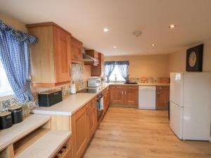 惠特比Rose Cottage的厨房配有木制橱柜和白色冰箱。