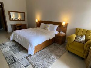 Maravilla Kivu Eco Resort的一间卧室配有一张床和一张黄色椅子