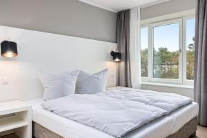 宾茨Strandresidenzen Strandresidenzen Haus Dänholm 3 1的卧室内的一张白色床,设有窗户