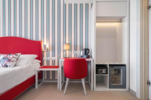 卡普多兰多Seaside Hotel的一间卧室配有一张床、一张红色椅子和一张书桌