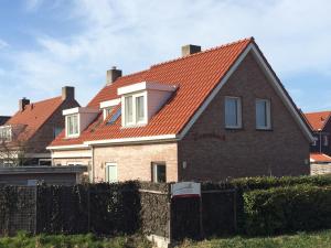 阿赫特克克Apartment Zonnehoek的一座带橙色屋顶和围栏的房子