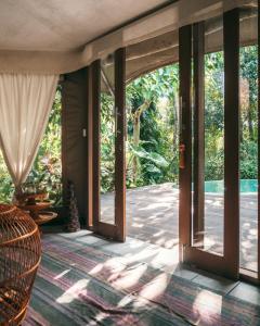 乌布散达特格拉姆平帐篷酒店的通往树木庭院的开放式玻璃门