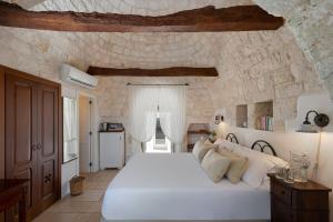 洛科罗通多阿普里勒马塞里亚酒店的卧室配有一张白色大床,位于石墙内