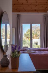 达拉索Villa Meltemi的一间卧室配有一张带镜子和紫色鲜花的床