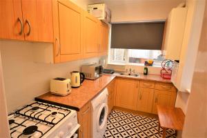 巴尔金Lovely 3 Bedroom House near Barking Station的厨房配有木制橱柜和炉灶烤箱。